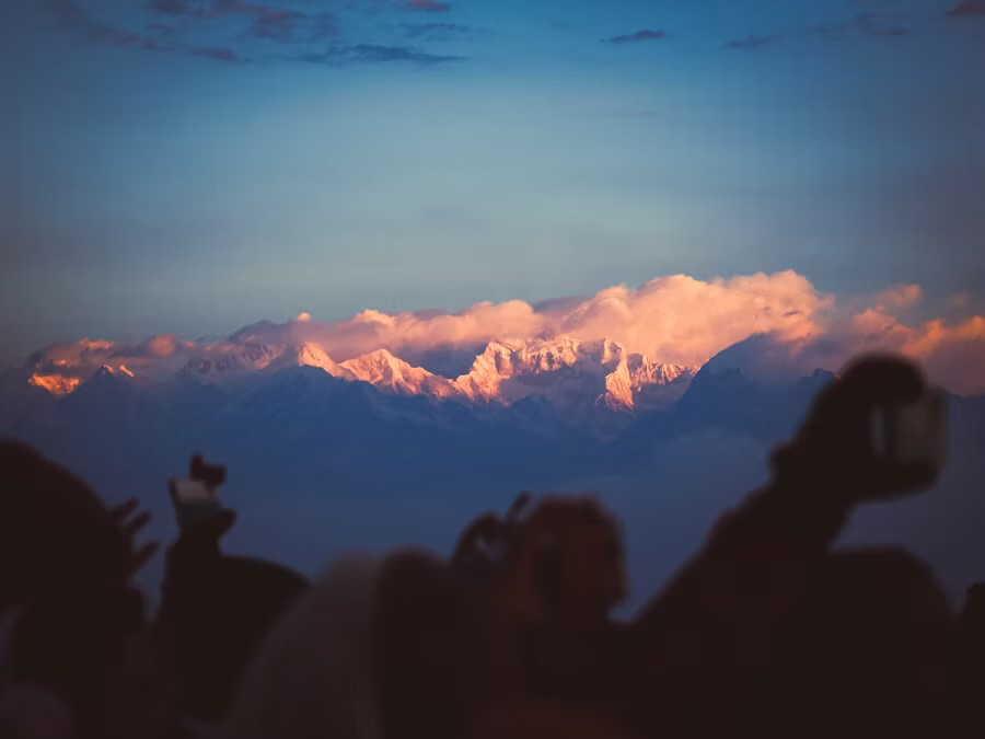Dawn light on the Khangchendzonga range seen from Tiger Hill, onlookers silhouetted in the foreground