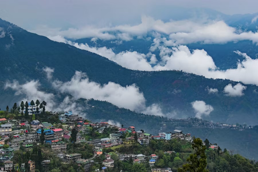 A hillside town of brightly painted houses with cloud filling the valley below