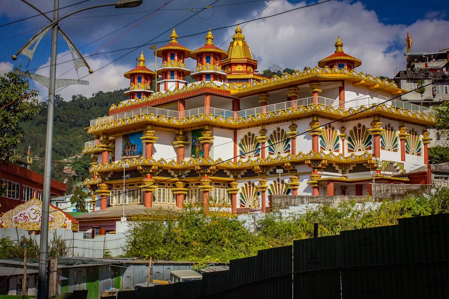 A brightly painted and gilded multi-tiered Hindu temple on a hillside in Gangtok