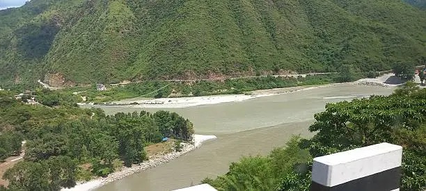 The wide Tista river running between green hills with the highway alongside