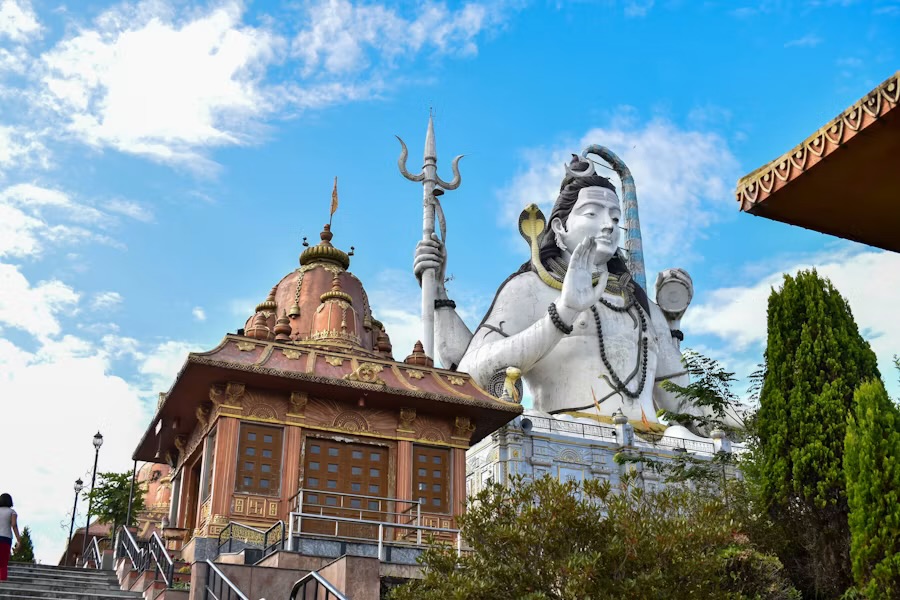 The tall white Shiva statue rising behind a temple roof at the Chardham complex in Namchi