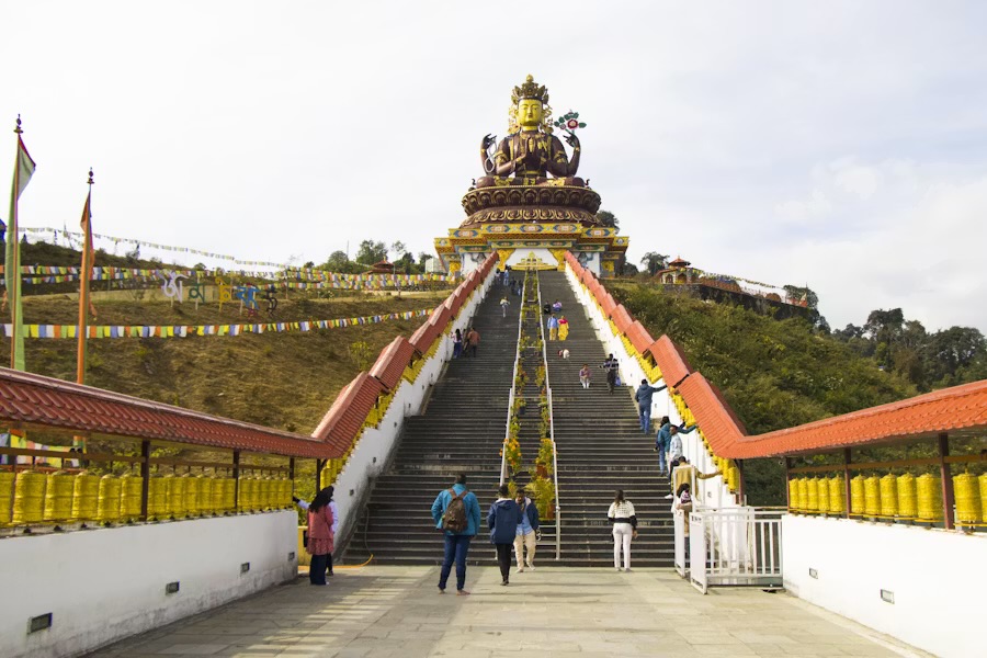 The gilded Chenrezig statue above its staircase and rows of prayer wheels at Pelling