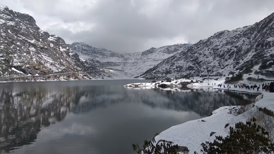 Tsomgo Lake under snow in East Sikkim, with visitors along the far shore