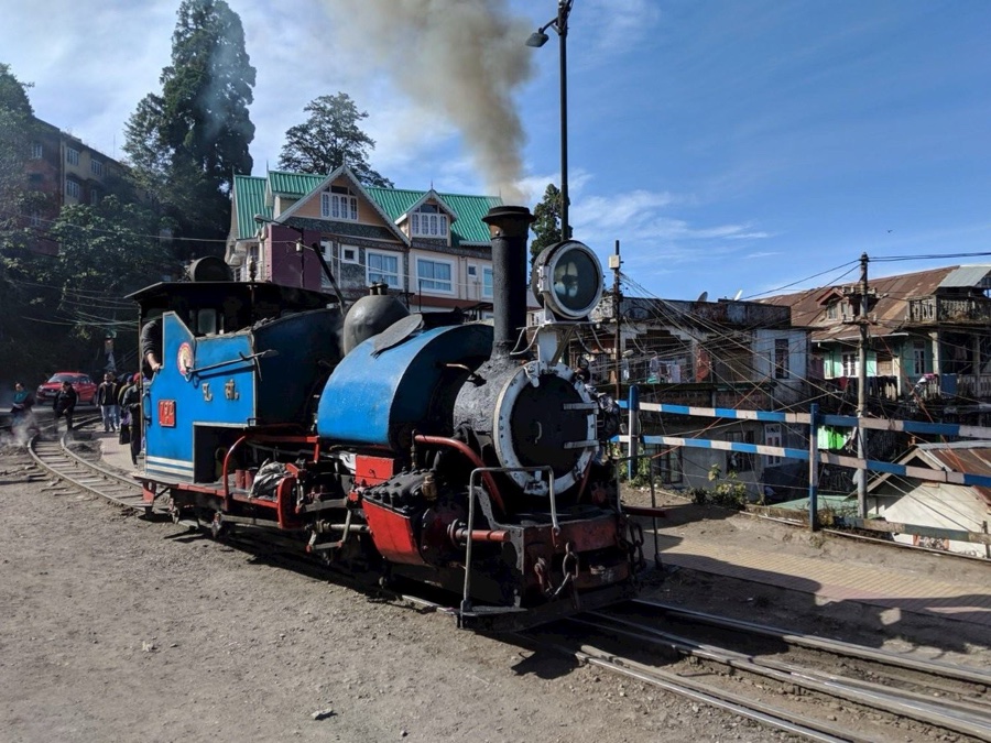 A blue steam locomotive of the Darjeeling Himalayan Railway standing at a hill station